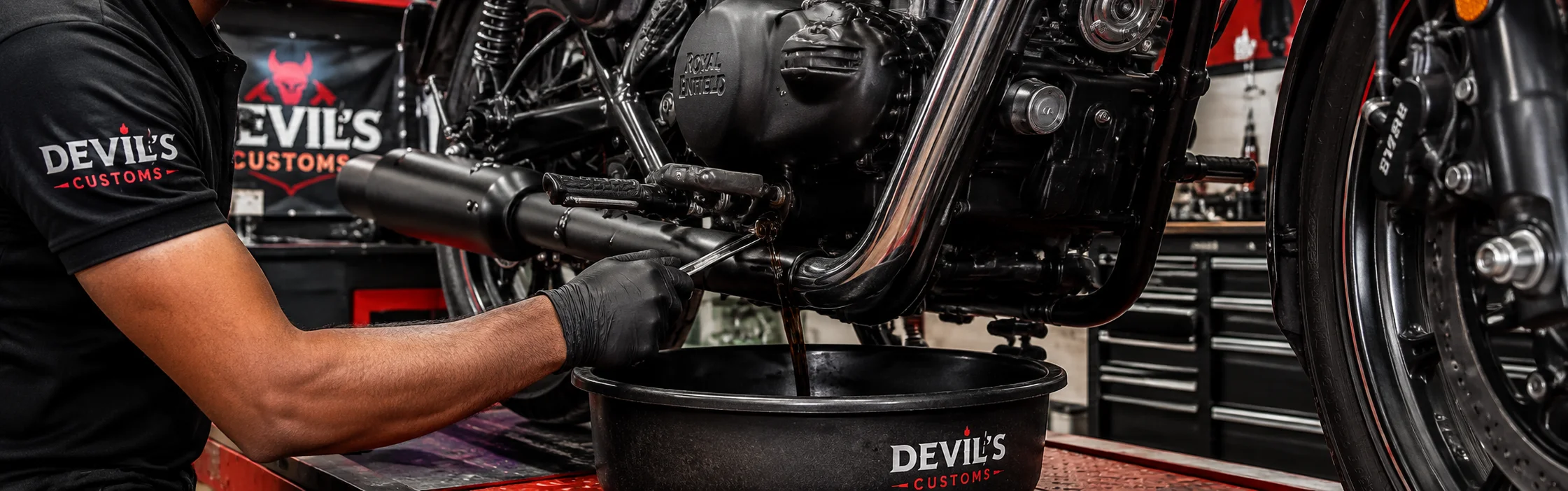 Mechanic performing an engine oil change during Royal Enfield maintenance at Devil's Customs